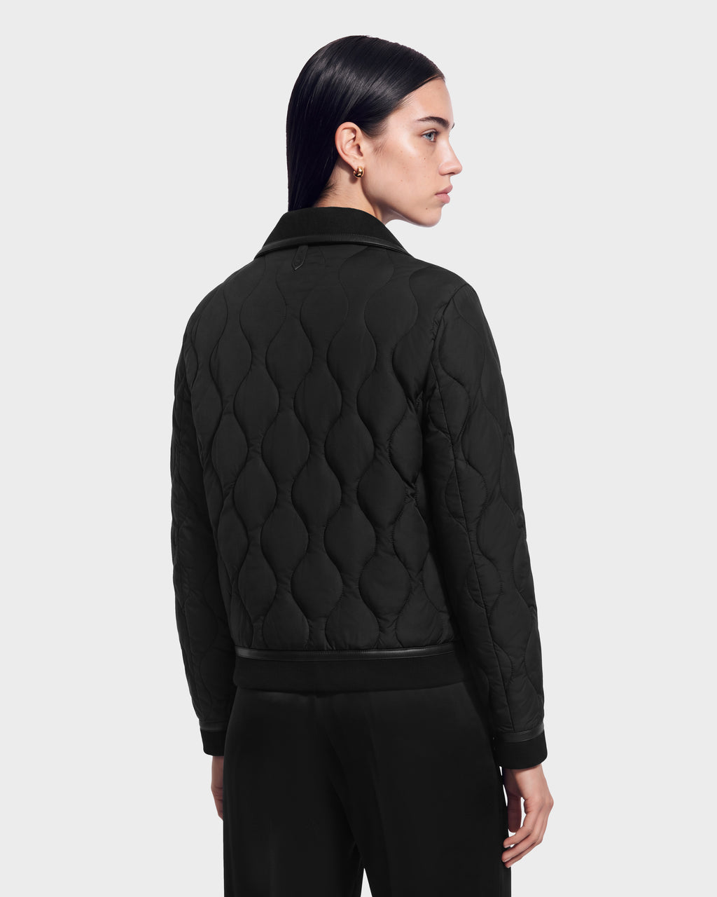 A person seen from behind wearing a black JOLIE - 8125036 RUDSAK quilted down jacket with a collar and ribbed trim.