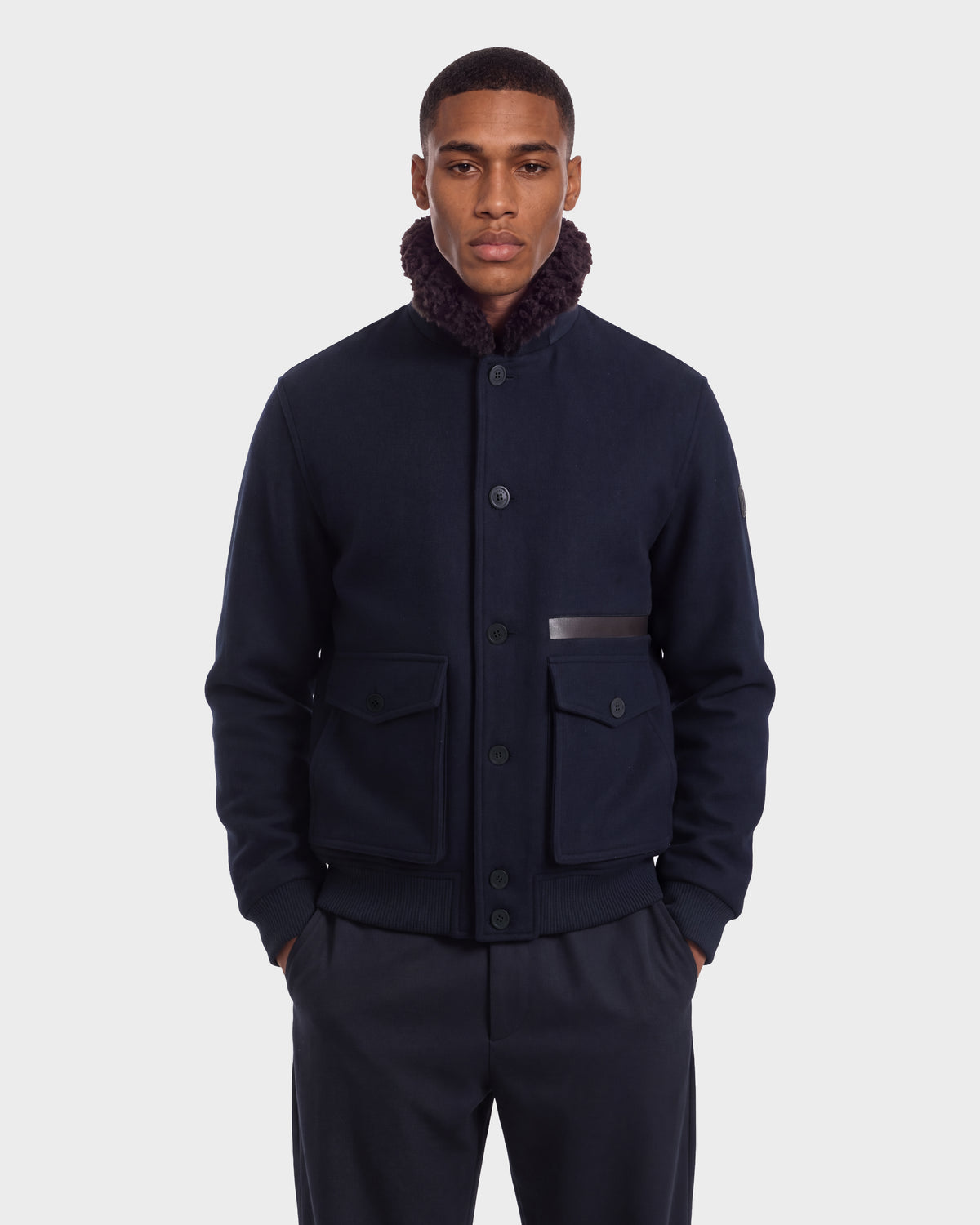 A man wearing a Rudsak JULIUS - 6126723 Navy wool-blend jacket featuring a dark shearling collar and buttoned flap pockets.