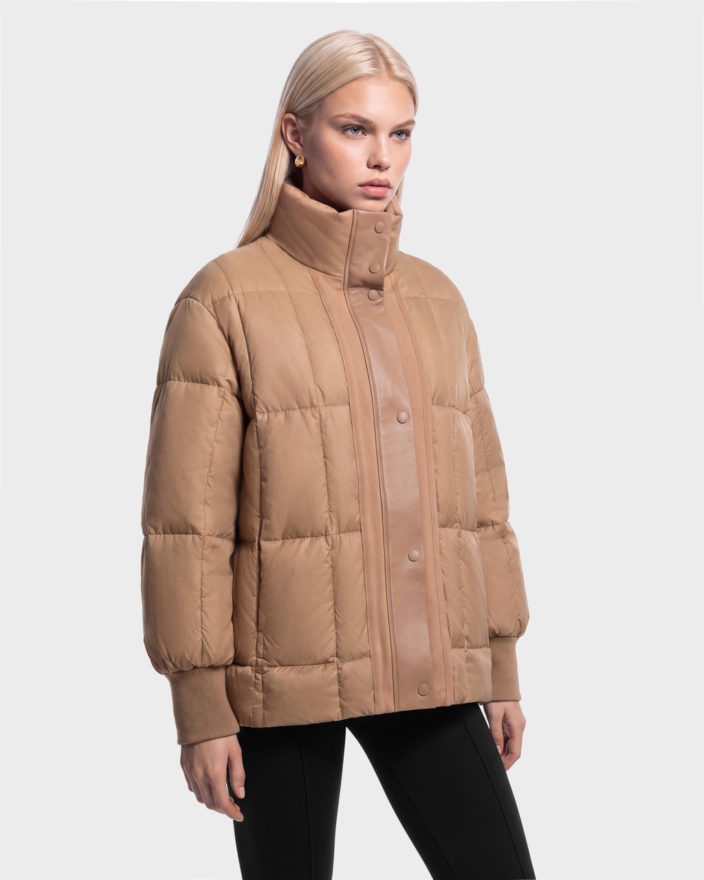 A woman wears a camel-colored ROSALINDA - 8126523 Camel quilted puffer jacket with a high collar and snap-button closure.
