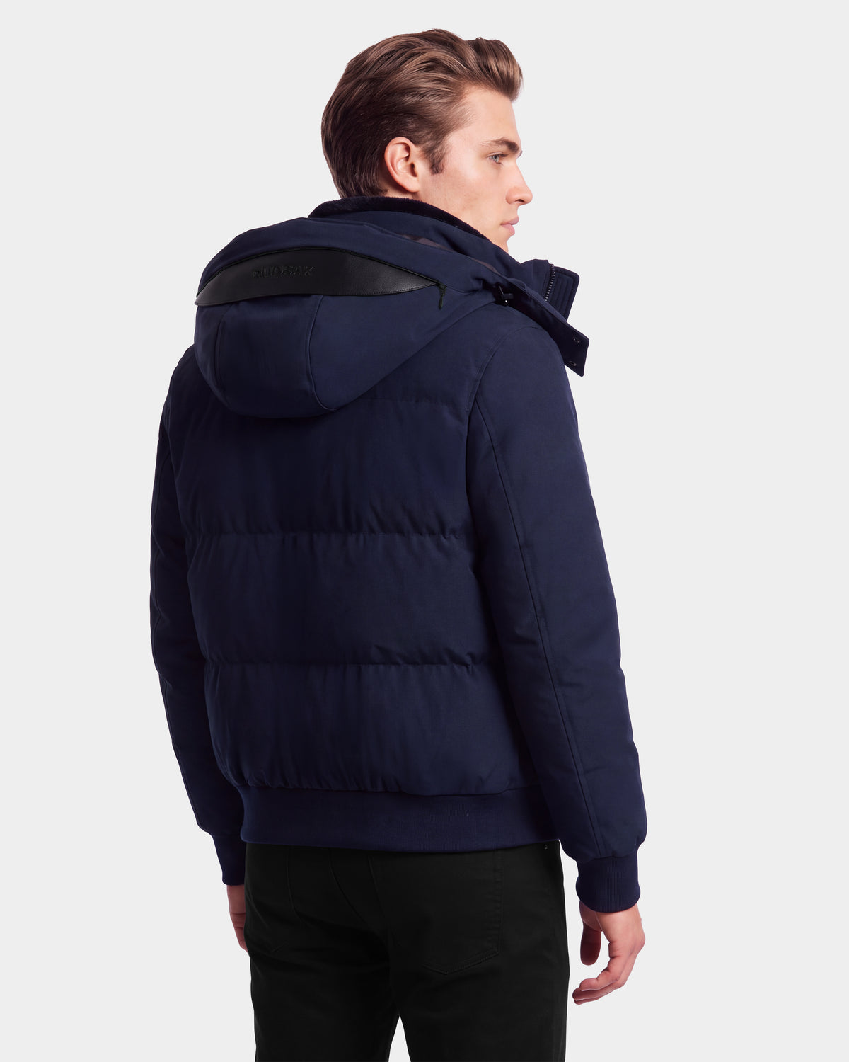 A man wearing the Rudsak WILL - 6126561 Navy puffer jacket with down insulation and a hood, seen from the back, stands against a plain white background.