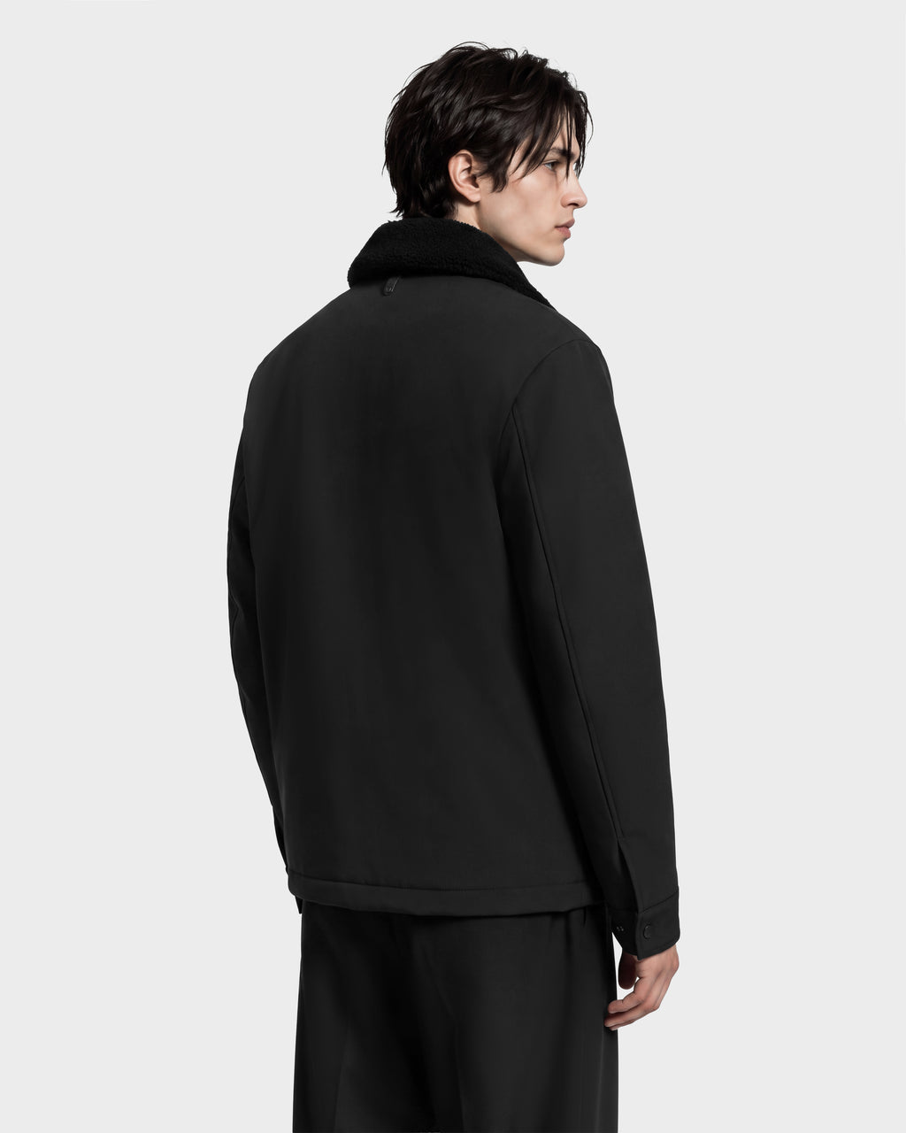 A man seen from behind wearing an ANTOINE - 6126506 Black utility jacket with a refined dark faux-fur collar.