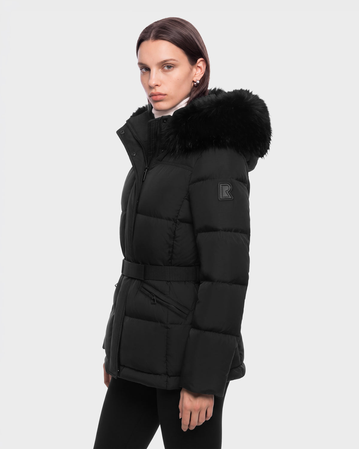 A person wearing a black Rudsak GRACE FF - 8126535 belted puffer jacket with a faux fur-trimmed hood.
