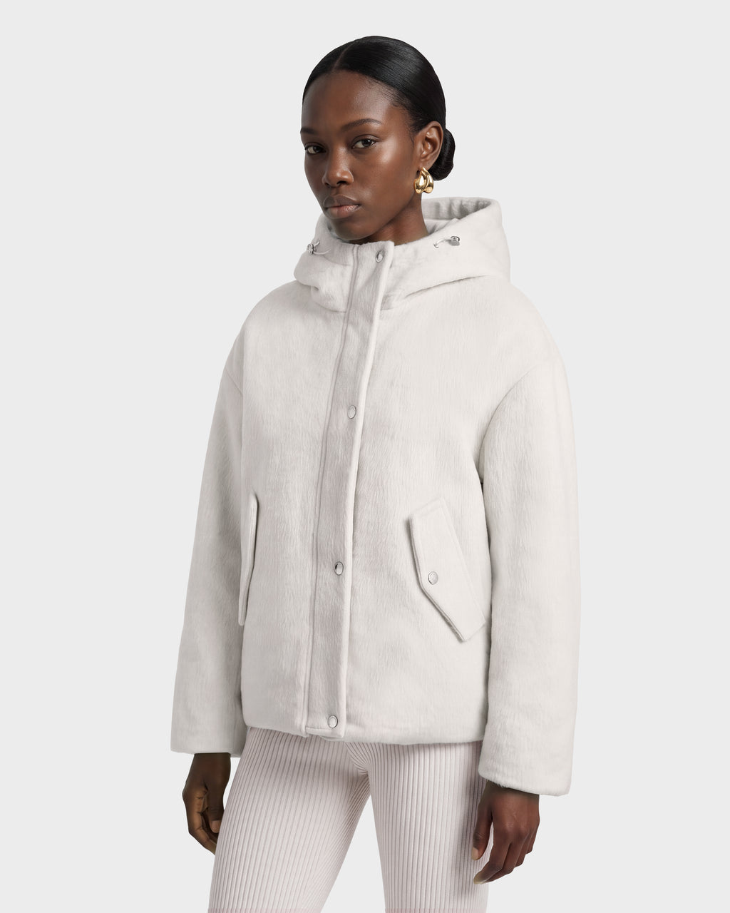 A person wears a Rudsak HAZEL - 8126981 Vanilla hooded, off-white wool-blend winter coat with a button-down front and side pockets.