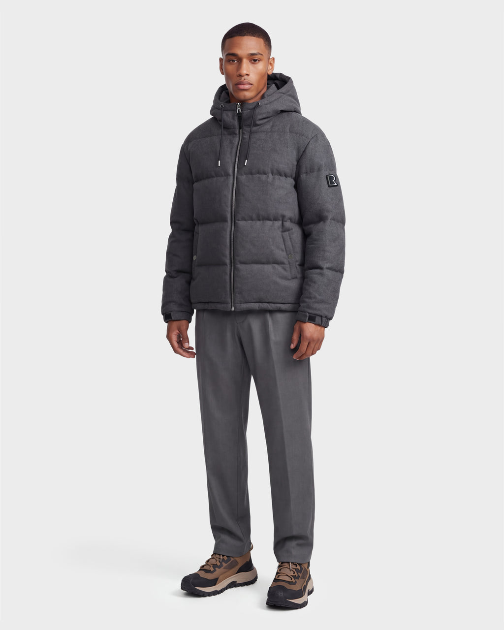 A man stands posed against a plain white background, wearing the Rudsak STERLING W - 6126760 puffer jacket in Heather Charcoal.