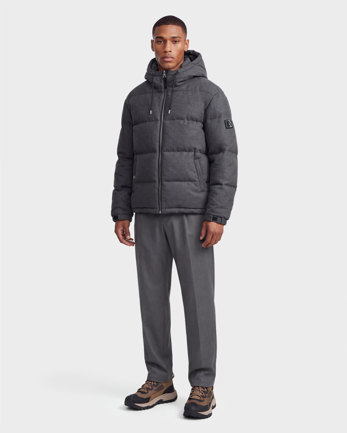 A man stands posed against a plain white background, wearing the Rudsak STERLING W - 6126760 puffer jacket in Heather Charcoal.