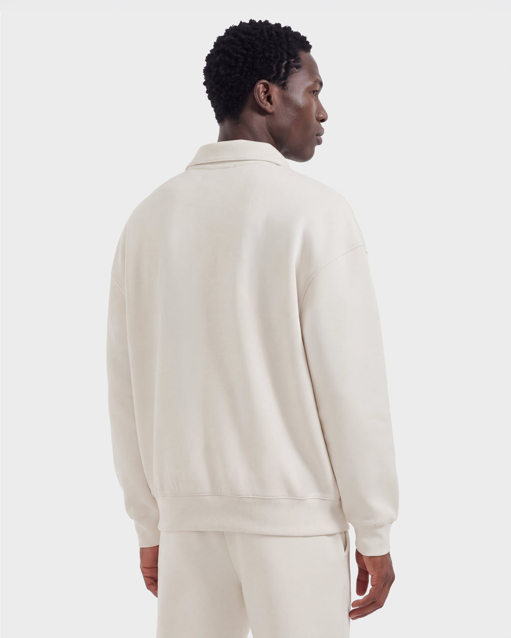 A person seen from the back wearing a cream-colored Rudsak IDRIS - 6526500 Vanilla men’s polo sweater and matching pants in a relaxed silhouette.