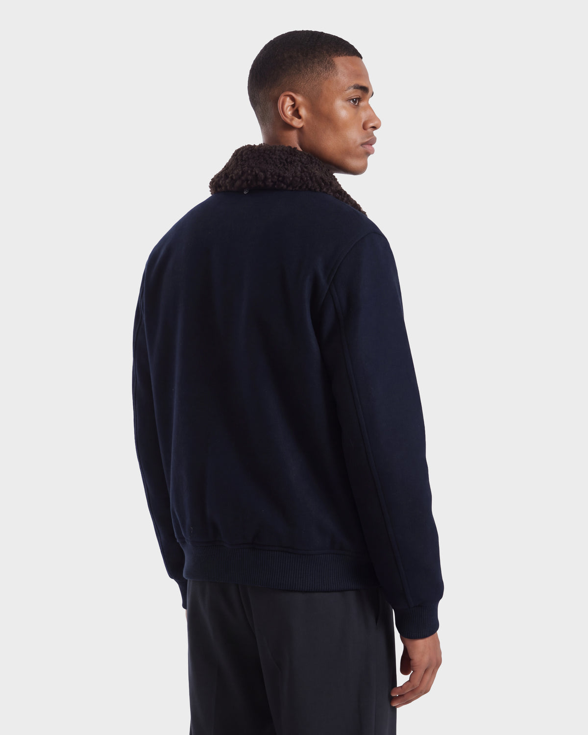 A man wearing a RUDSAK JULIUS - 6126723 Navy bomber jacket with a brown textured collar.