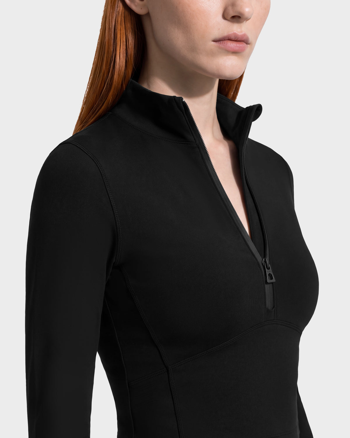 A person wearing a black Rudsak ANITA - 8526579 athletic long-sleeve top featuring a cropped silhouette, a mock neck, and a partial front zipper.