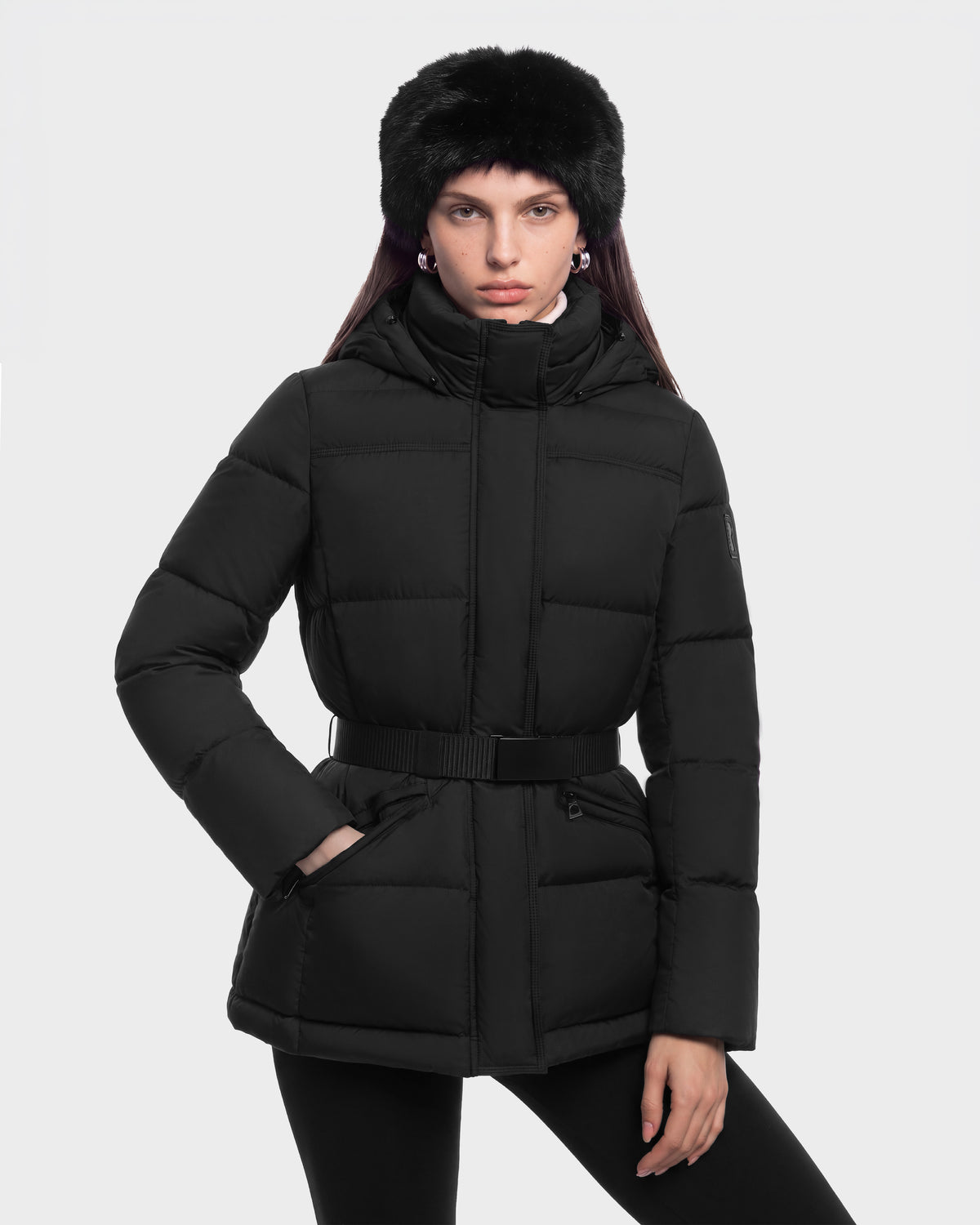 A person wearing a black GRACE FF - 8126535 Black hooded puffer jacket with a belted waist and a black faux fur hat.