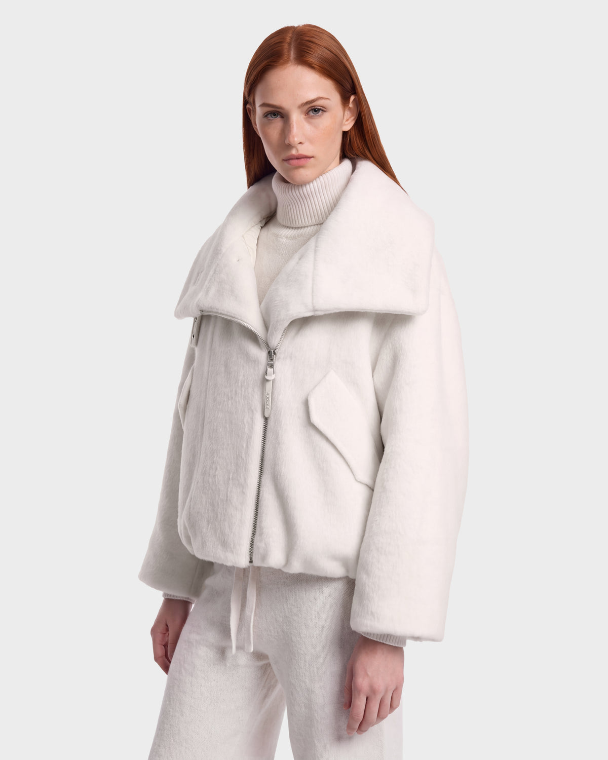 Woman wearing a white ZARIA - 8126999 Vanilla zip-up winter puffer with a faux-fur collar and a matching turtleneck sweater.