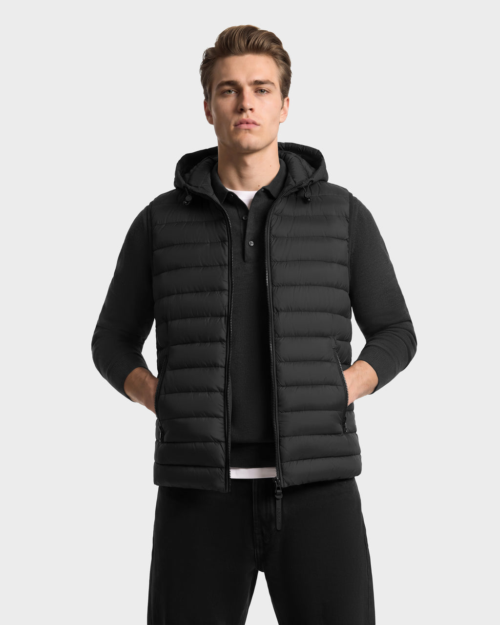 A man wearing a BRUNO - 6126716 Charcoal hooded puffer vest over a long-sleeved polo shirt.