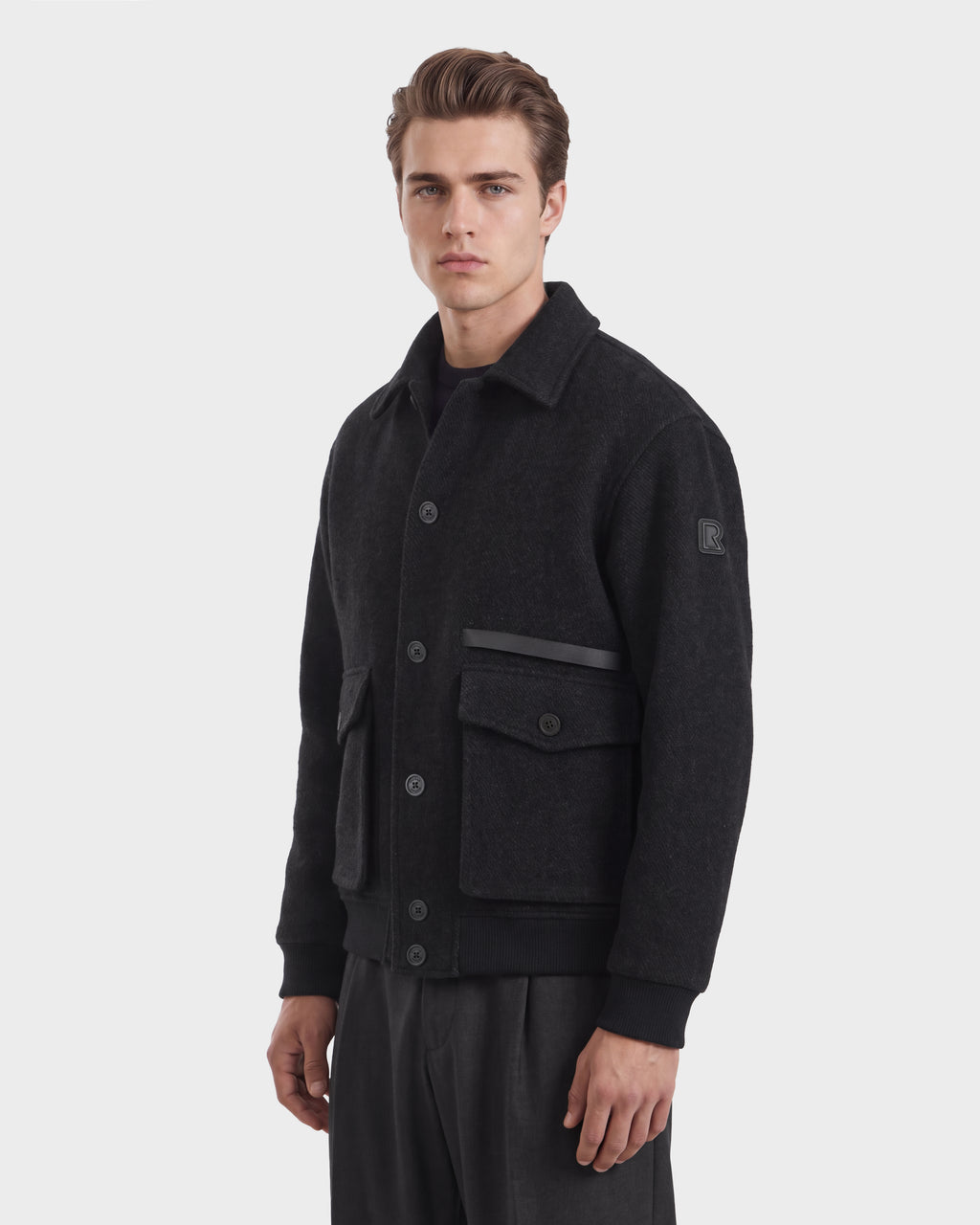 A man wearing a charcoal Rudsak JULIUS 6126723 dark gray wool-blend button-down jacket with two front pockets and ribbed cuffs.