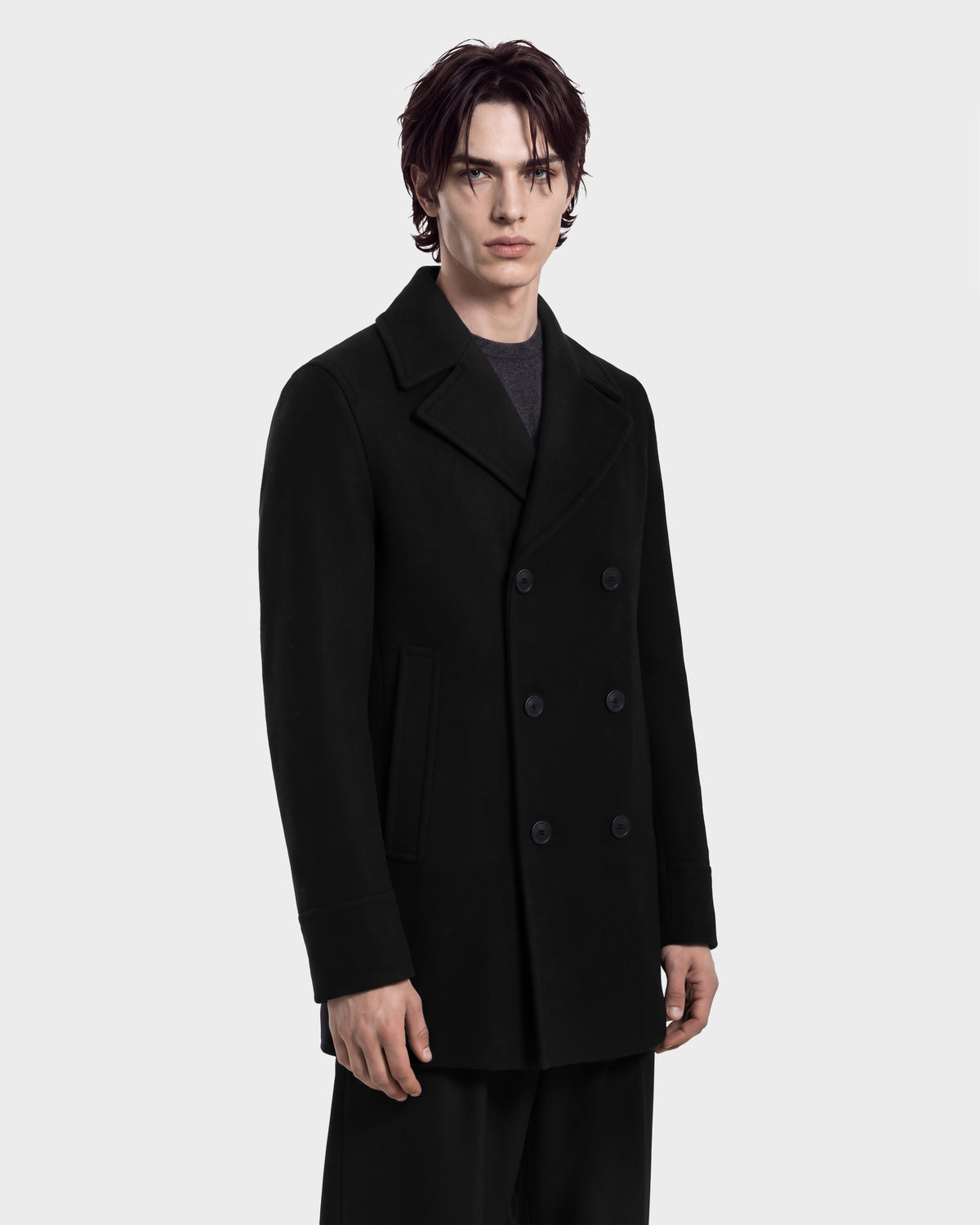 A man wears a black Rudsak LUCIEN - 6126508 double-breasted wool-blend pea coat with a wide collar over a dark shirt.