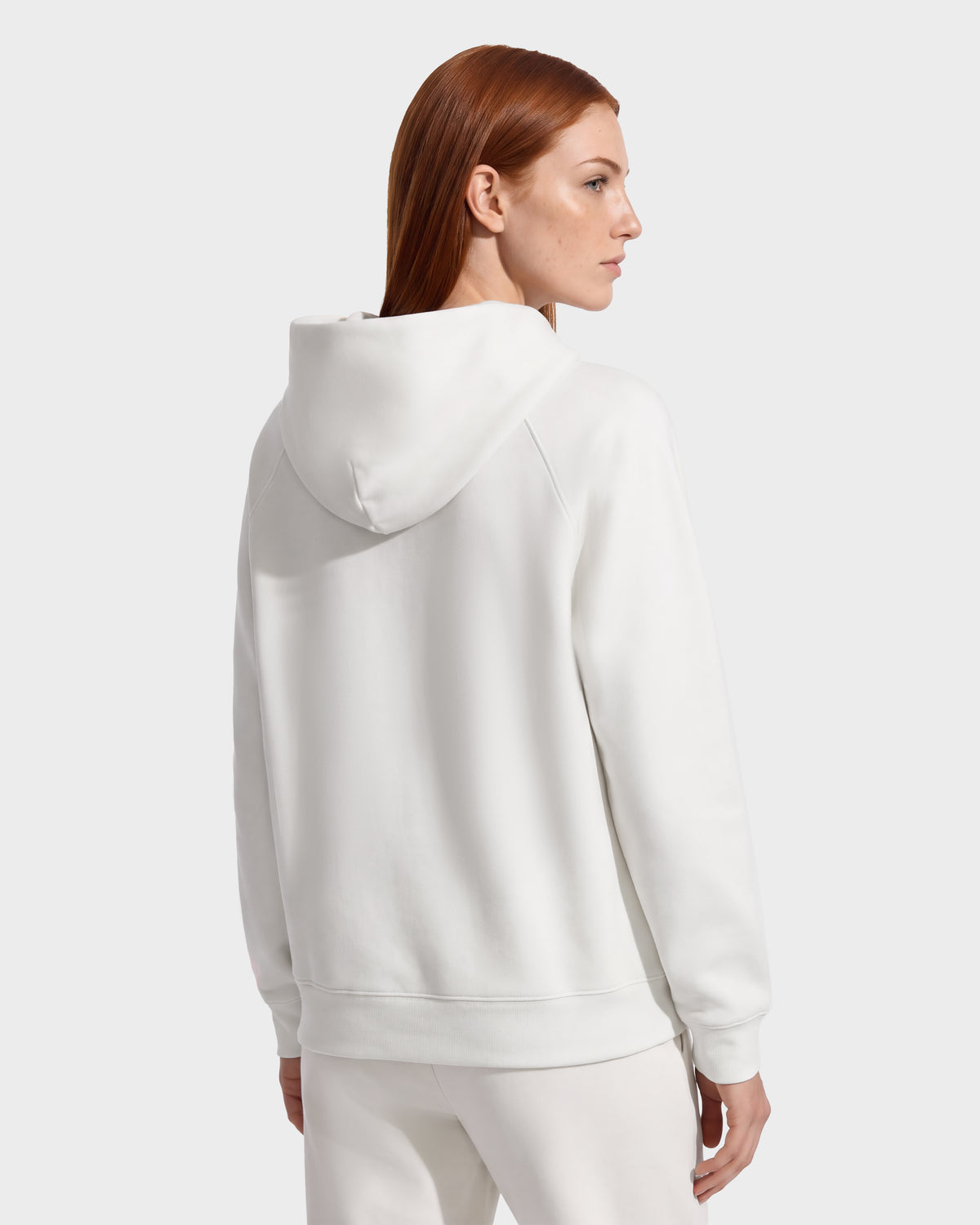 A person viewed from the back wearing a white RUDSAK BRIAR - 9525001 Vanilla W unisex hoodie.