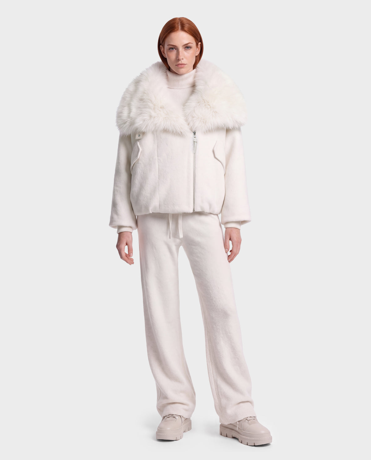 A model wearing a vanilla-colored ZARIA - 8126999 Vanilla winter puffer zip-up jacket with a large faux-fur collar, matching sweatpants, and light-colored sneakers.