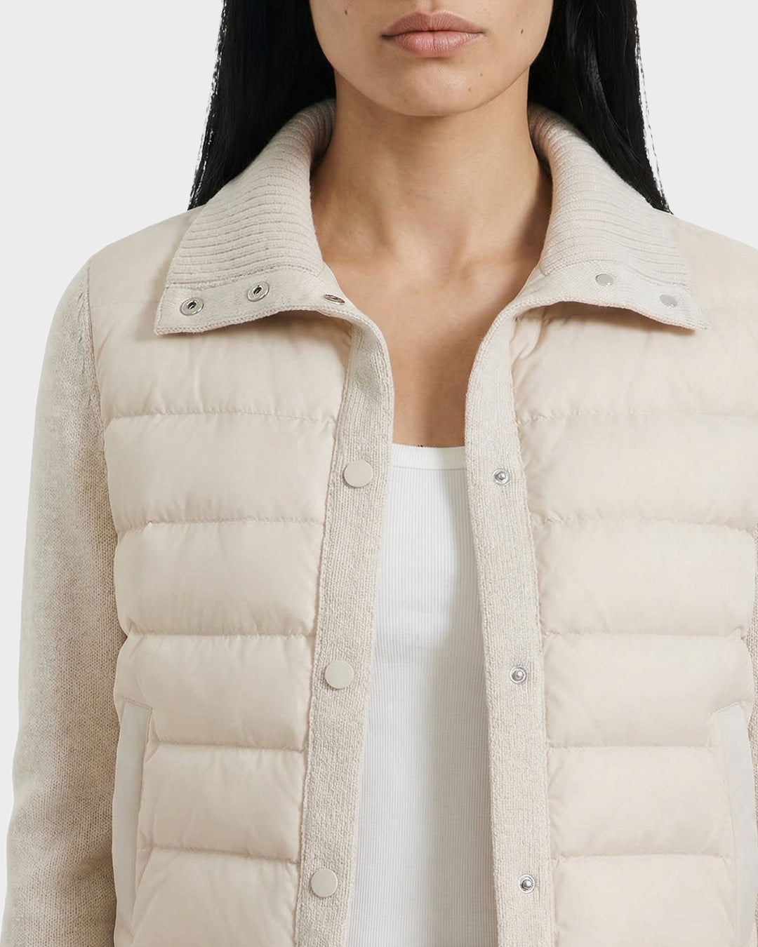 A woman, shown from shoulders to mid-torso, wears the Rudsak ELLIE - 8125635 Vanilla hybrid down jacket with a ribbed collar over a white top.