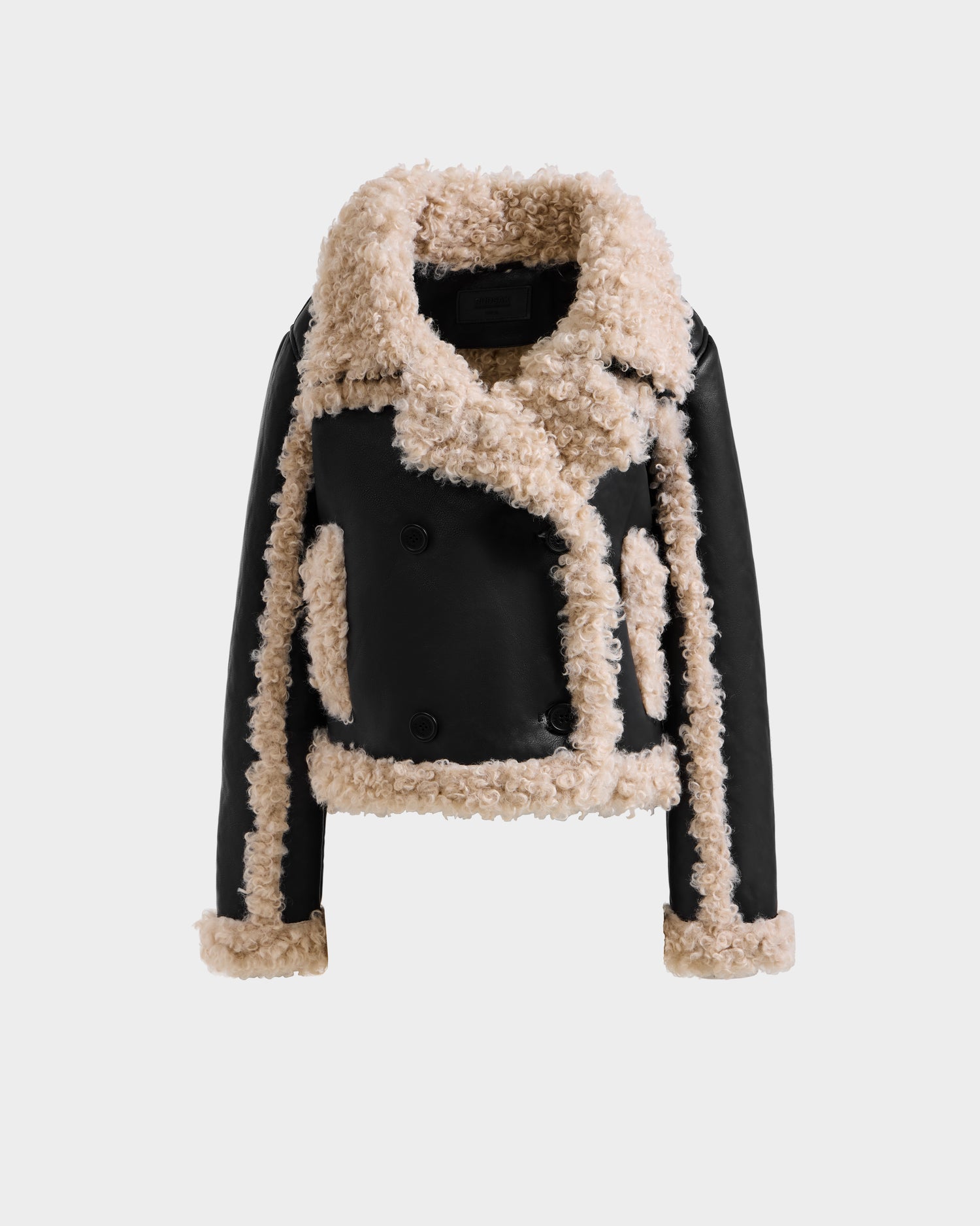 The EMERY - L125548 Black by Rudsak is a cropped women’s vegan-leather jacket with plush beige faux shearling trim on the collar, lapels, sleeves, and pockets, shown on a plain white background.