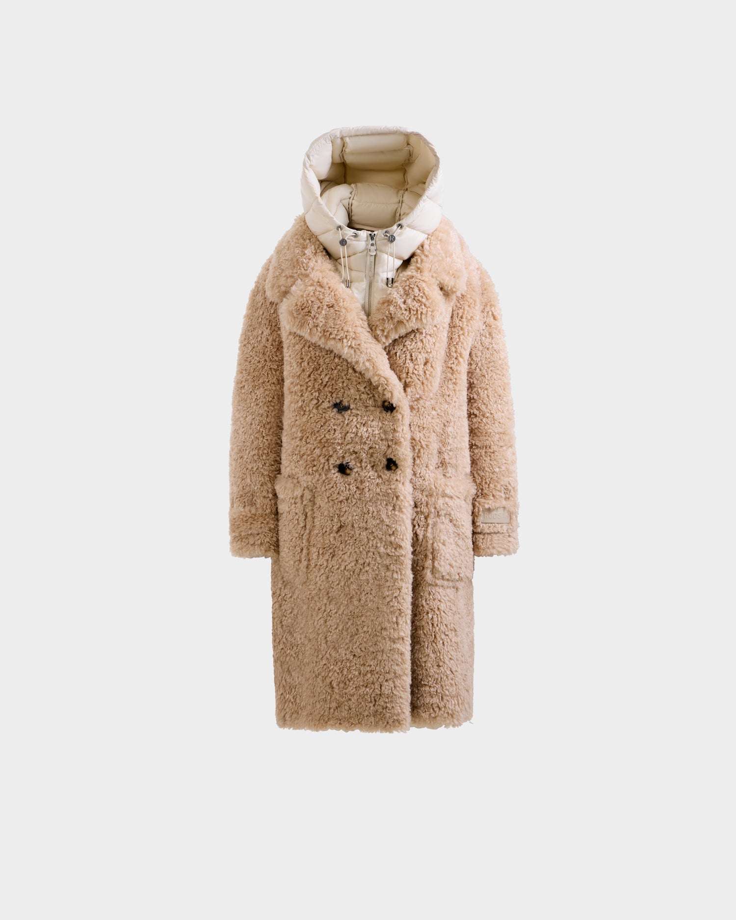 The EMRYN - L125588 Vanilla by Rudsak is a long, beige, double-breasted faux fur women's winter coat with large buttons, a light quilted hood, two spacious front pockets, and a cozy texture, shown on a plain light background.