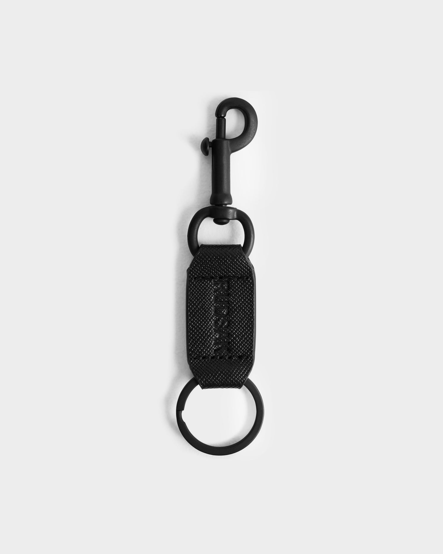 The Rudsak RYLIE - M424500 Black keychain features a fabric strap, metal key ring, and swivel snap hook—ideal for men’s box sets or with a reversible leather belt, showcased on a simple light background.
