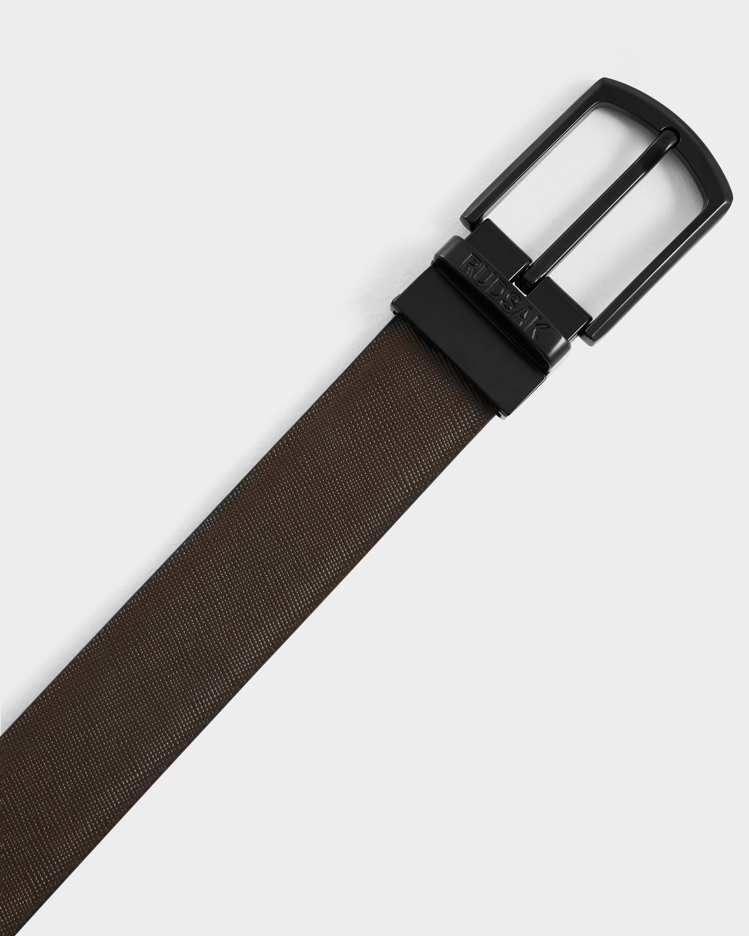 The RYLIE - M424500 Black belt by Rudsak features a textured reversible leather design and a black rectangular buckle, displayed diagonally on a plain background—perfect for men’s box sets or as an elegant gift addition.