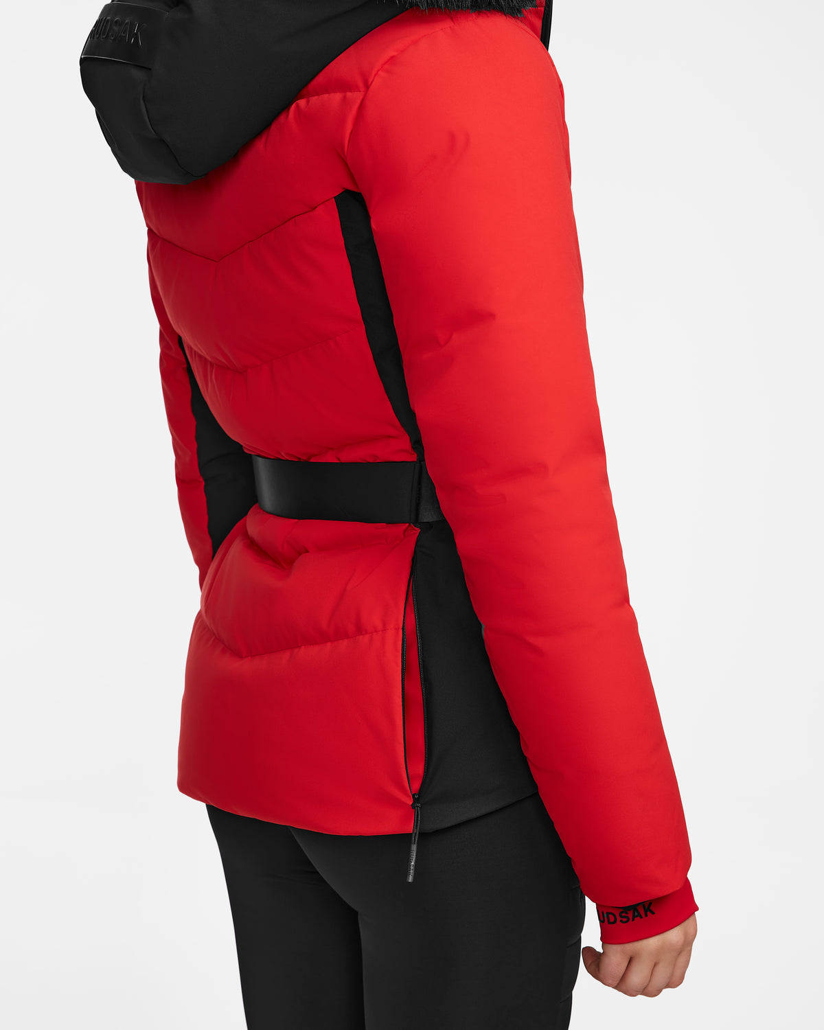 A person is shown from the side against a white background wearing Rudsak’s ALAIA - 8124816 Flame Red fitted ski jacket with black accents, a belt, black hood, and matching black pants.