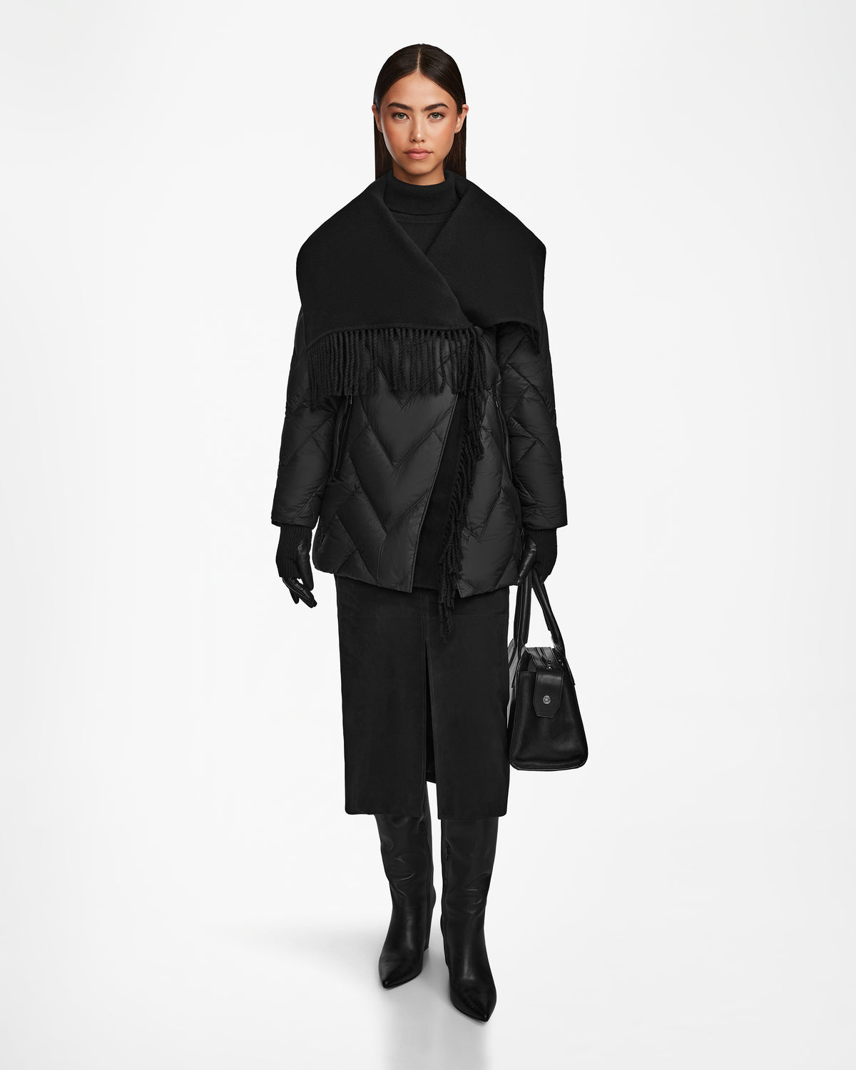 A woman stands facing forward against a white background, wearing Rudsaks ANNE MARIE - 8124713 Black quilted down wool jacket with a large scarf, black gloves, skirt, knee-high boots, and holding a black handbag.