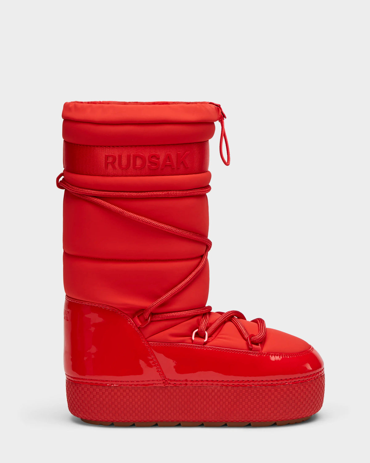 The FARAH - 8223501 Flame Red by Rudsak is a bright red women’s high-top winter boot with a thick sole, glossy water-repellent lower, quilted upper, wraparound laces, and embossed Rudsak branding for bold style and protection.