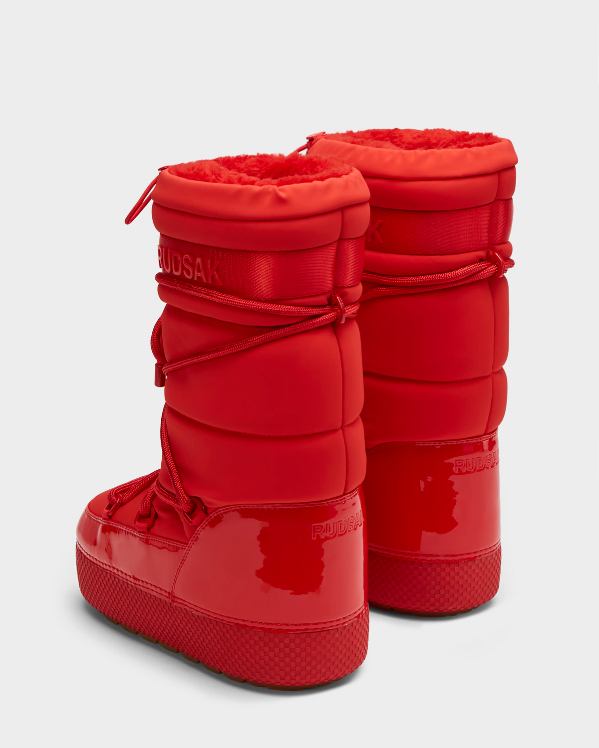 A pair of FARAH - 8223501 Flame Red high-top women’s winter boots by Rudsak, featuring glossy and matte finishes, thick soles, laces, visible branding, and a cozy faux fur lining, shown from the back and side on a plain background.