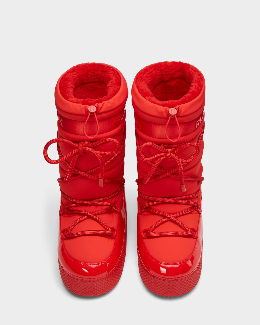 A pair of FARAH - 8223501 Flame Red womens winter boots by Rudsak with glossy toes, thick soles, and fleece lining. These water-repellent, tall moon boots have crisscrossed laces and a round shape, displayed on a white background.
