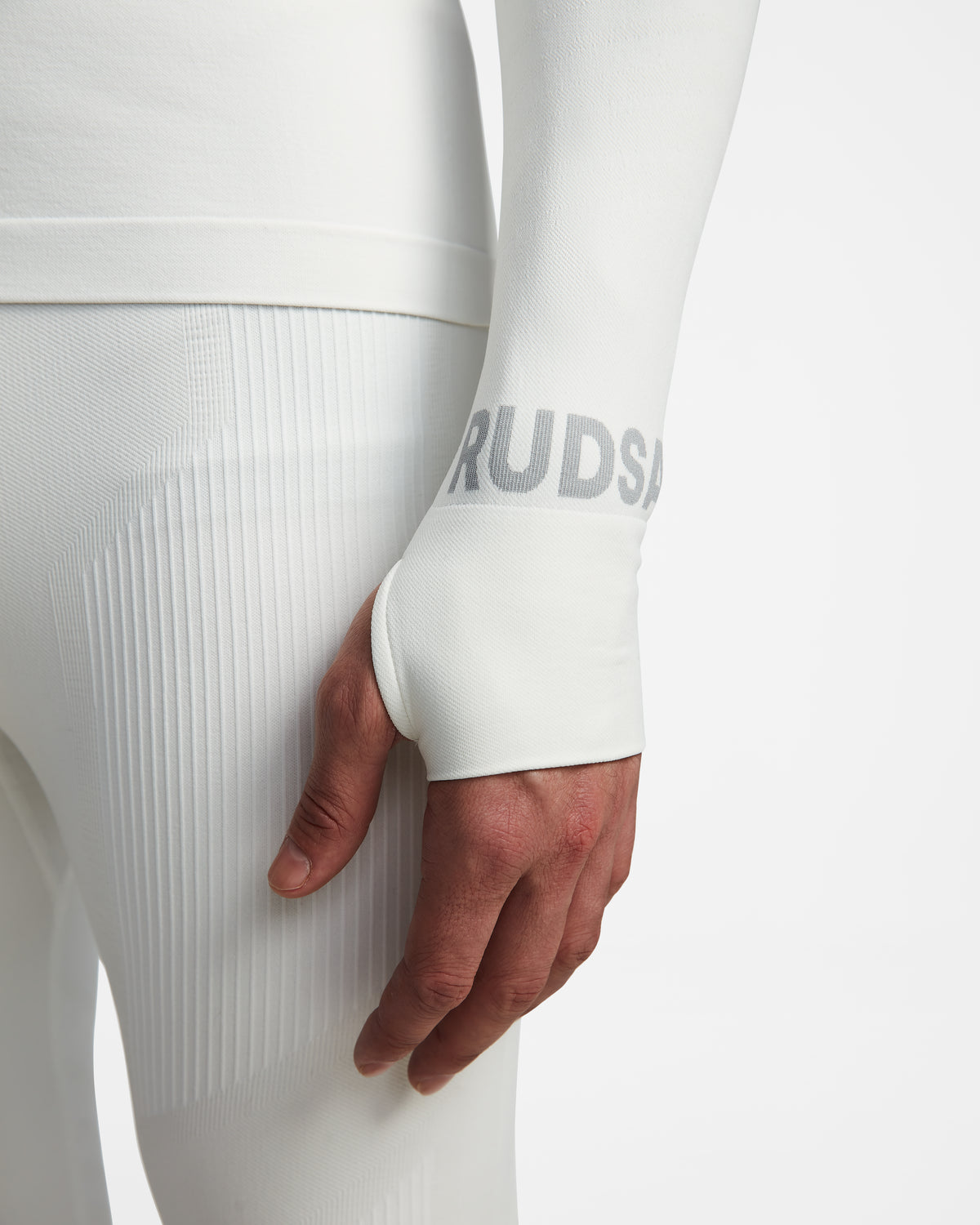 A close-up of a person wearing the Rudsak FRANC - 6524541 Iceland white base layer, showing their right hand and hip. The sleeve has a thumb hole and partial RUDSA text in light gray.