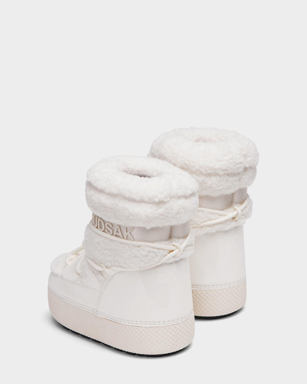Rudsak KATHY Y - 1224500 Iceland: White water-repellent winter boots with thick, fluffy cuffs, patent finish, laces, and textured soles. RUDSAK branding appears near the top. Boots displayed on a white background.