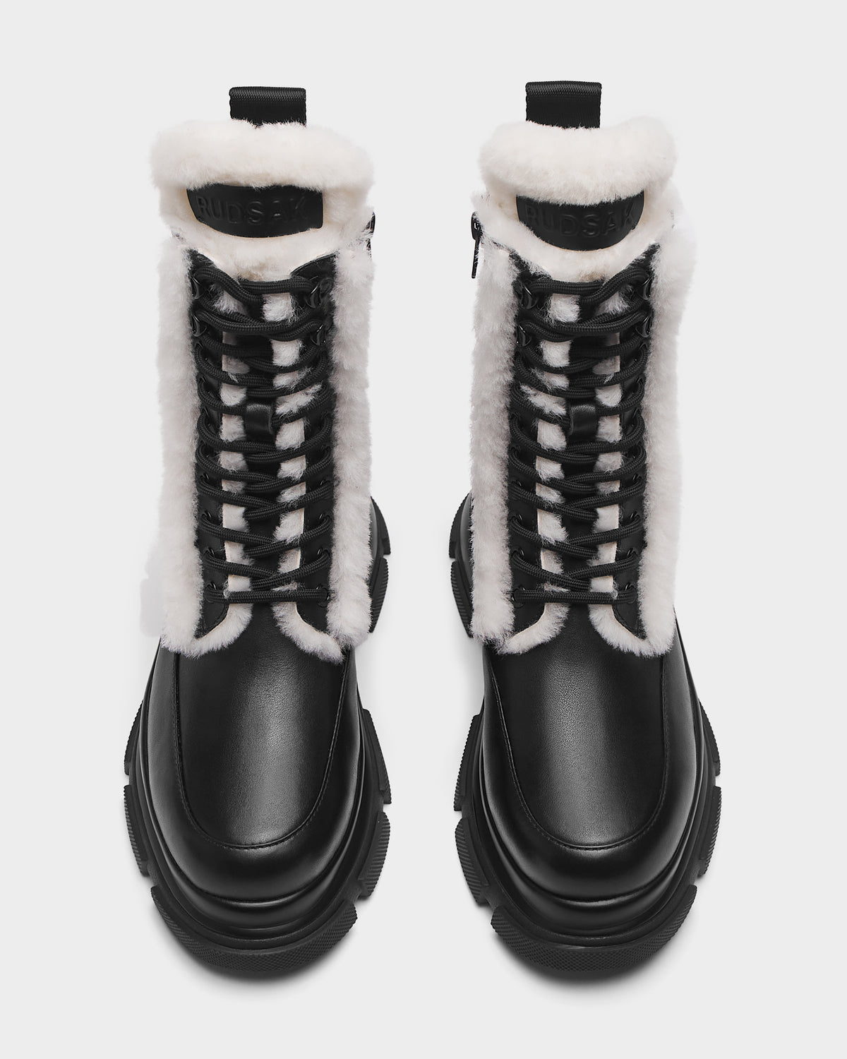 The Rudsak LANA S - 8224537 Black boots are black leather shearling boots with thick white trim and black-and-white laces, shown from above on a white background.