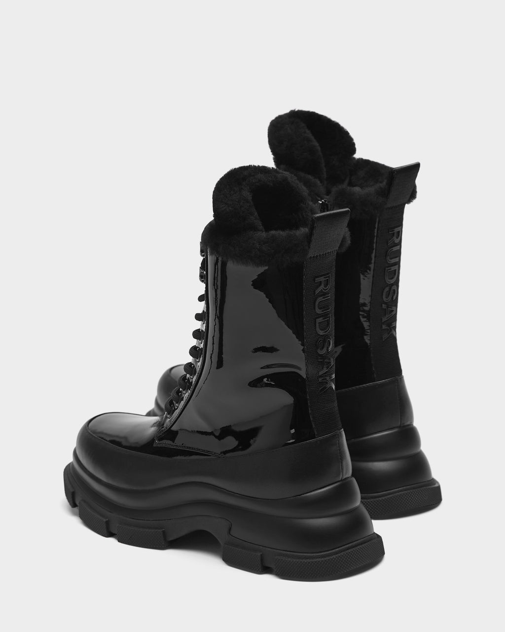 The LANA - 8223506 BLACK by Rudsak are shiny black mid-calf womens boots with chunky soles, plush shearling lining, and a back pull tab labeled RUDSAK—ideal for winter.
