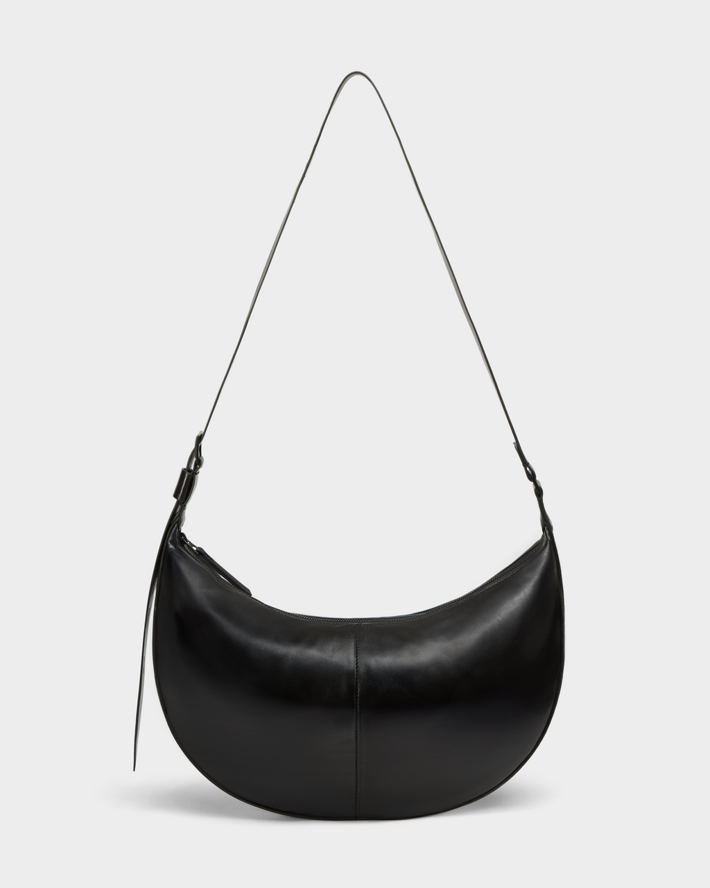 The LANISSA - 8324505 Black by Rudsak is a black crescent-shaped womens leather bag with a long, thin strap and minimalist design, shown against a plain light gray background.