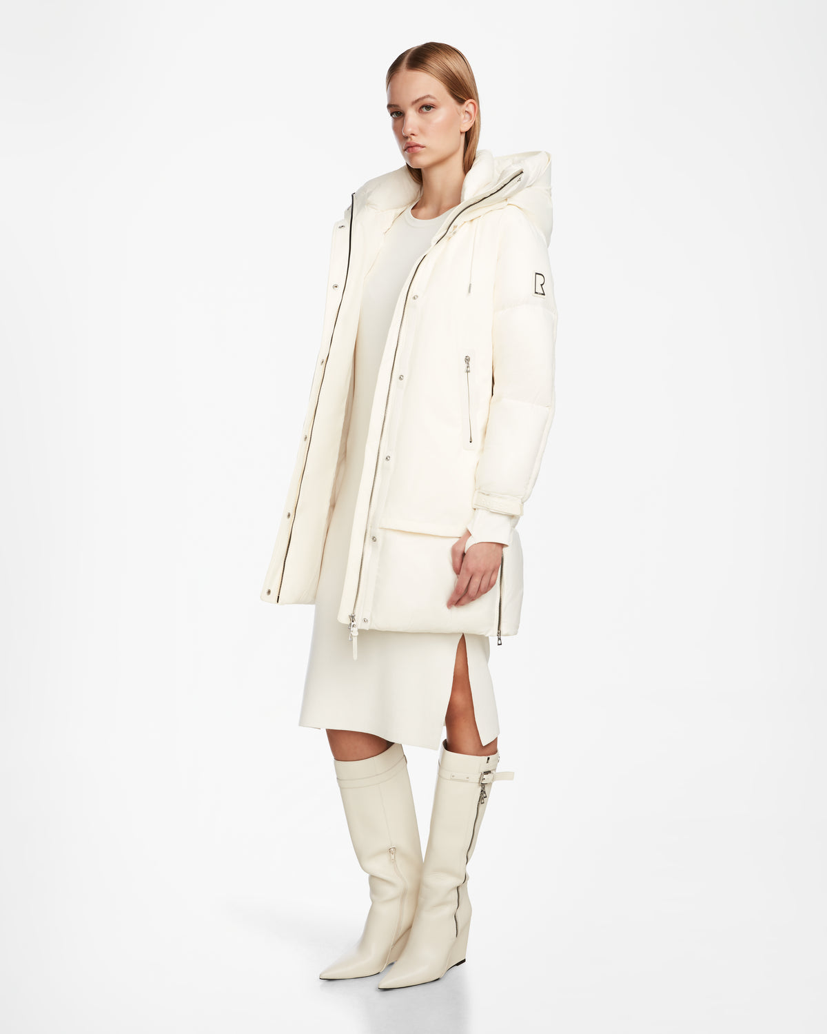 A woman models the LAYAN - 8124576 Iceland cream vegan leather coat by Rudsak over a matching dress and knee-high boots, standing against a plain white background and looking slightly to the side.