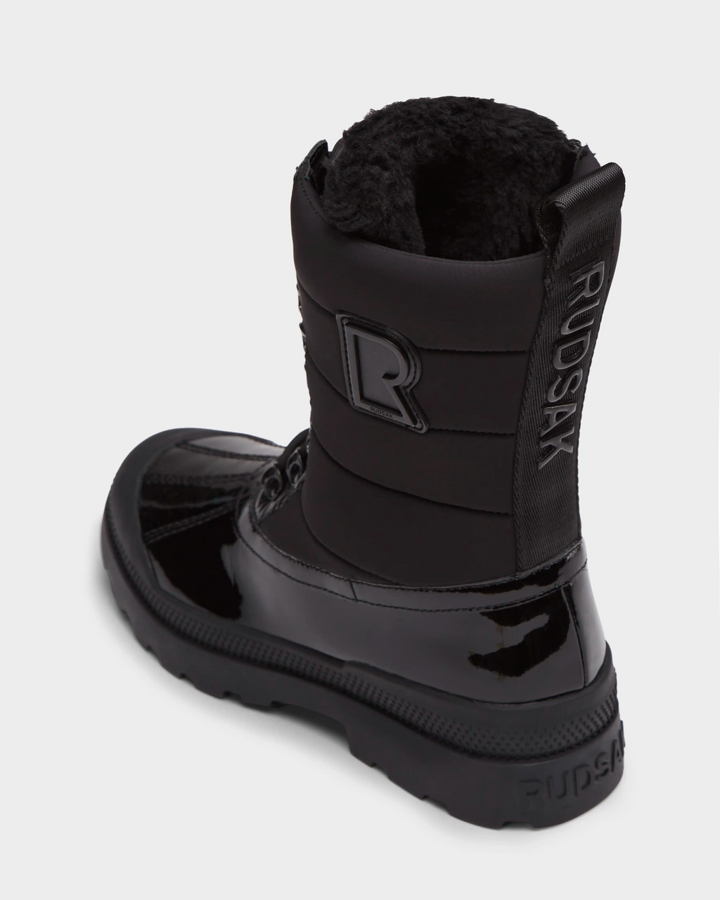 The LEX - 8224534 Black by Rudsak is a women’s winter boot with a shiny finish, thick sole, plush faux fur lining, water-resistant design, and cold weather comfort. Features include a vertical RUDSAK label and raised R logo on the back.