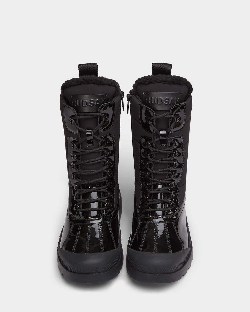 A pair of Rudsak LEX - 8224534 women’s black lace-up winter boots with thick soles and fur lining, seen from the front on a plain white background. The tongues display RUDSAK branding.