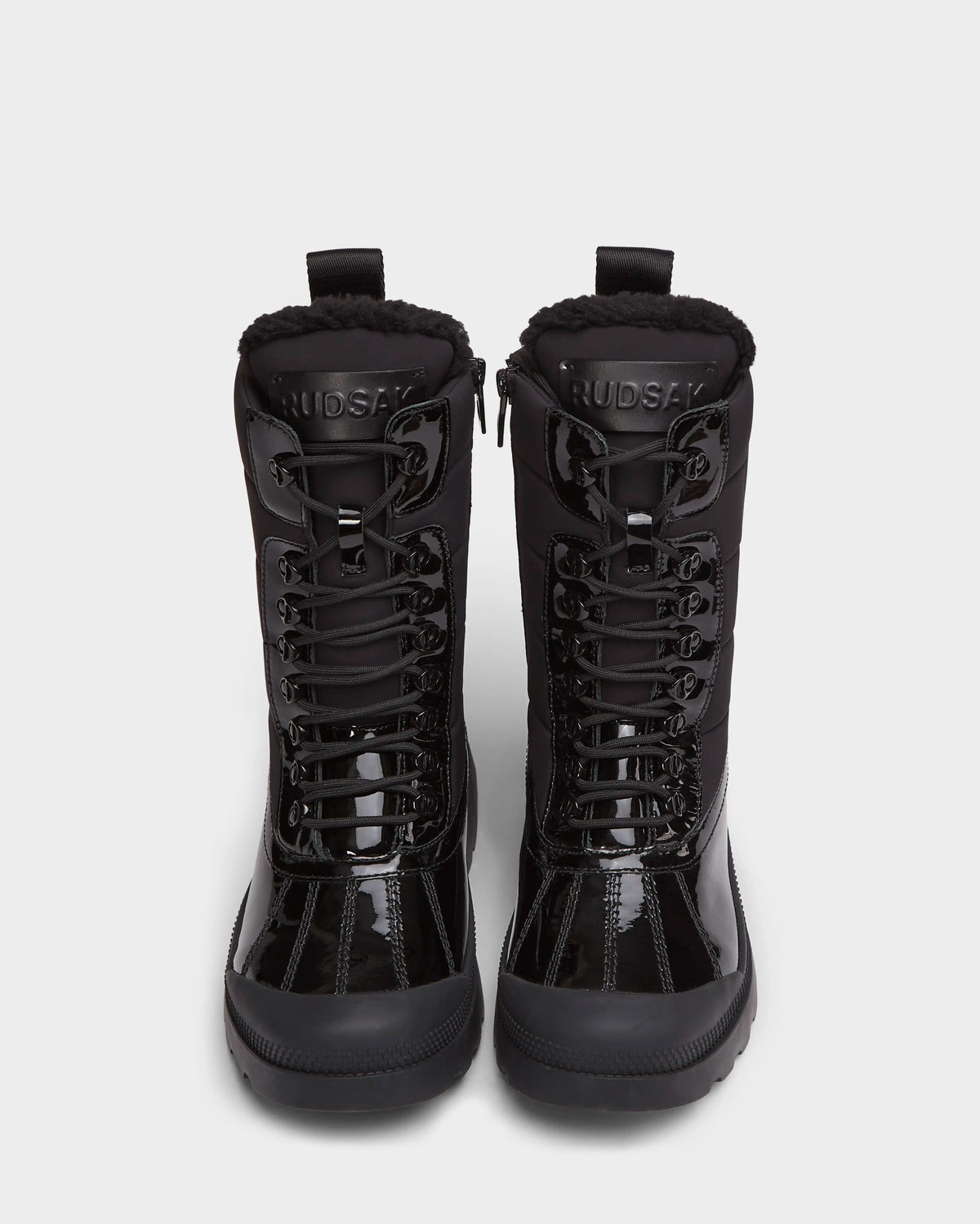 A pair of Rudsak LEX - 8224534 women’s black lace-up winter boots with thick soles and fur lining, seen from the front on a plain white background. The tongues display RUDSAK branding.