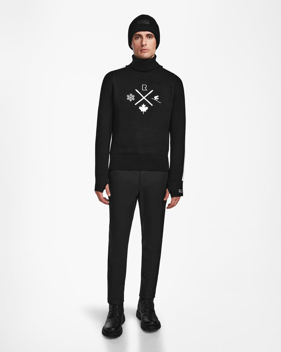 A person models the OLIVIER - 6524545 Black mens ski turtleneck sweater by Rudsak, paired with a black beanie, pants, and boots against a white background—ideal for an effortlessly stylish winter look.