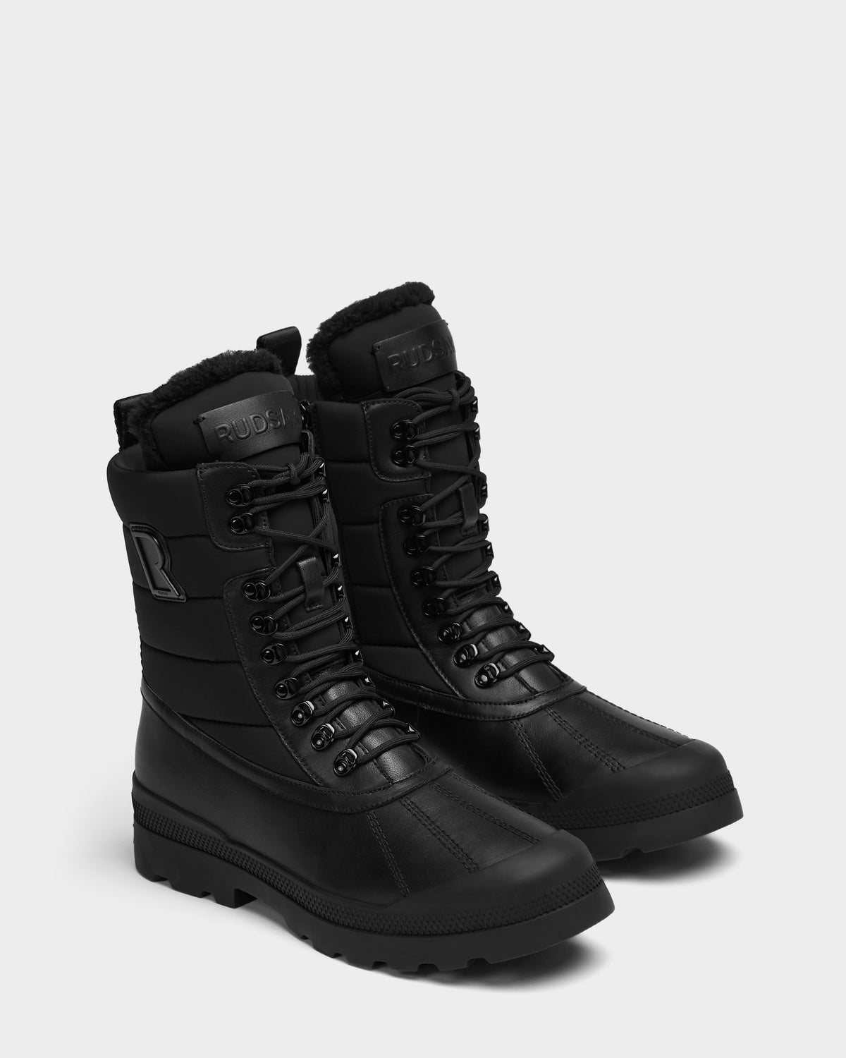Pair of black REAGAN - 6225046 Rudsak men’s winter boots featuring lace-up fronts, fur-lined collars, and lugged soles.