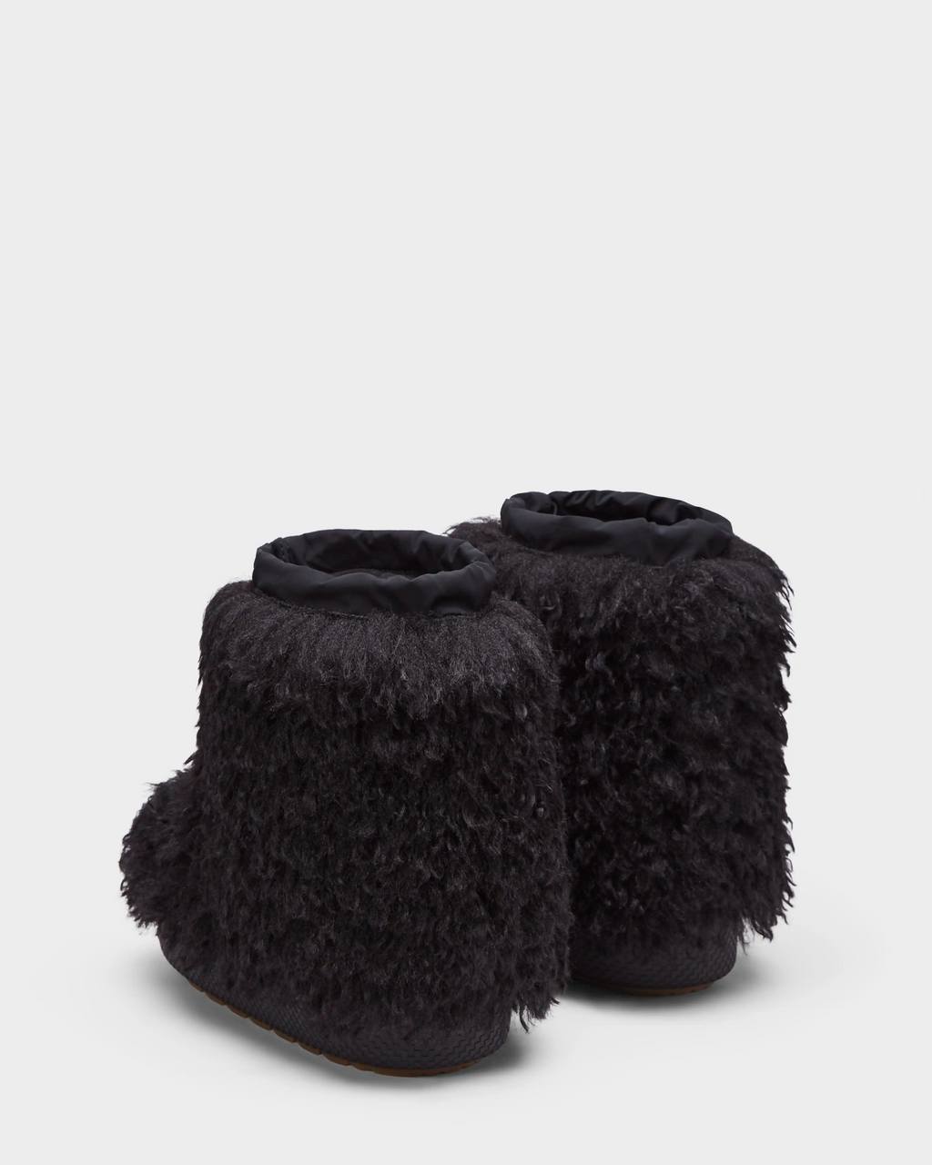 The ROSSY - 8224518 Black women's ankle-high slip-on winter boots by Rudsak feature a furry exterior, rounded toes, and soft fabric cuffs—shown from the back and side on a plain white background, ideal for cozy après-ski relaxation.