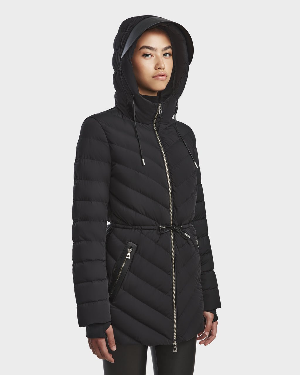 A person models the Rudsak FRANCINE - 8124722 Black puffer coat with a hood, quilted RDS-certified down, zippered pockets, and cinched waist, standing against a plain white background.