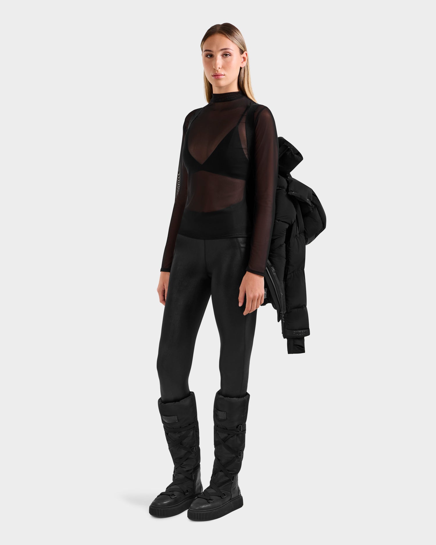 A woman poses against a light gray backdrop, wearing all black and holding the Rudsak ALESSANDRA S-M - L125551 Black cropped down puffer over one shoulder—her must-have cold-weather essential.