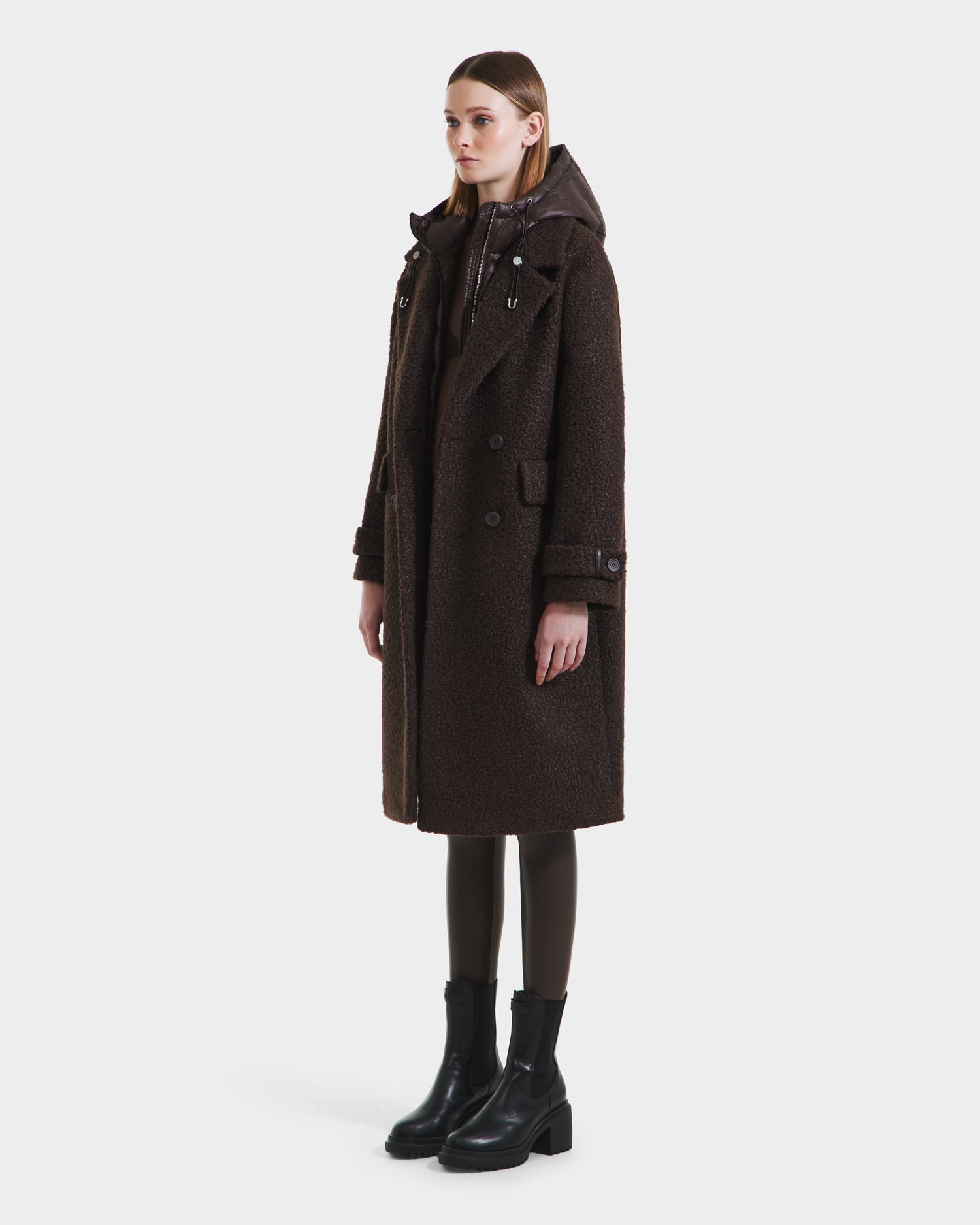 A woman faces forward in the ARABELLA - 8125621 Espresso overcoat by Rudsak, paired with black leggings and ankle boots, set against a plain white background.