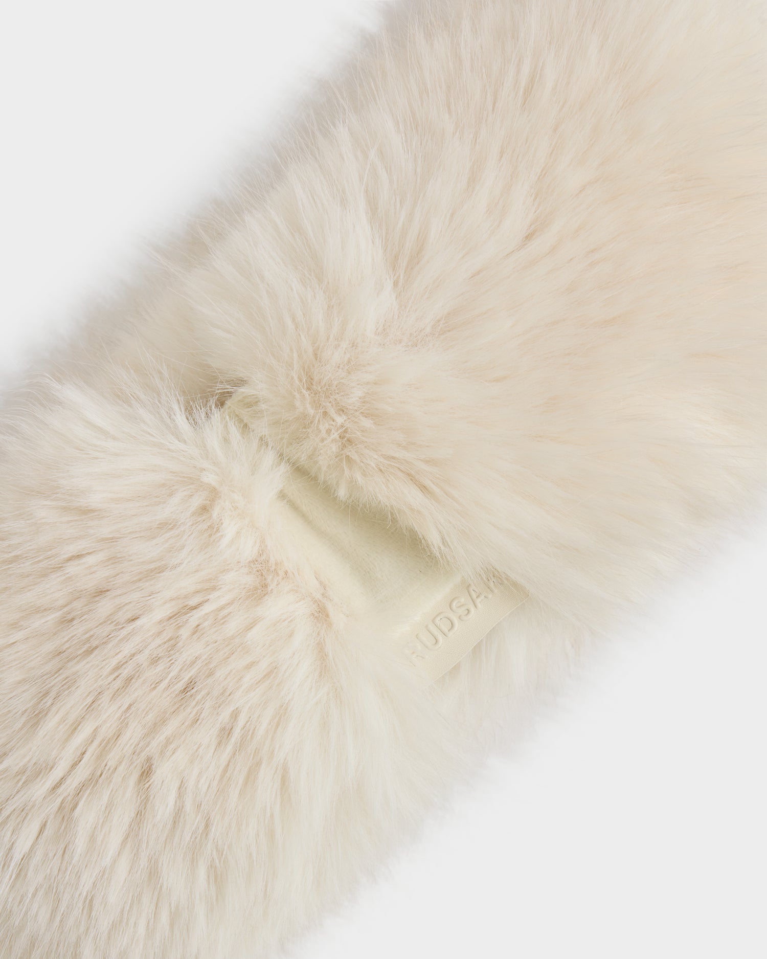 A close-up of the ARLETTE - 8425544 Vanilla women’s faux fur headband by Rudsak, in fluffy cream with cozy-chic style and a beige embossed tag—a perfect winter accessory.