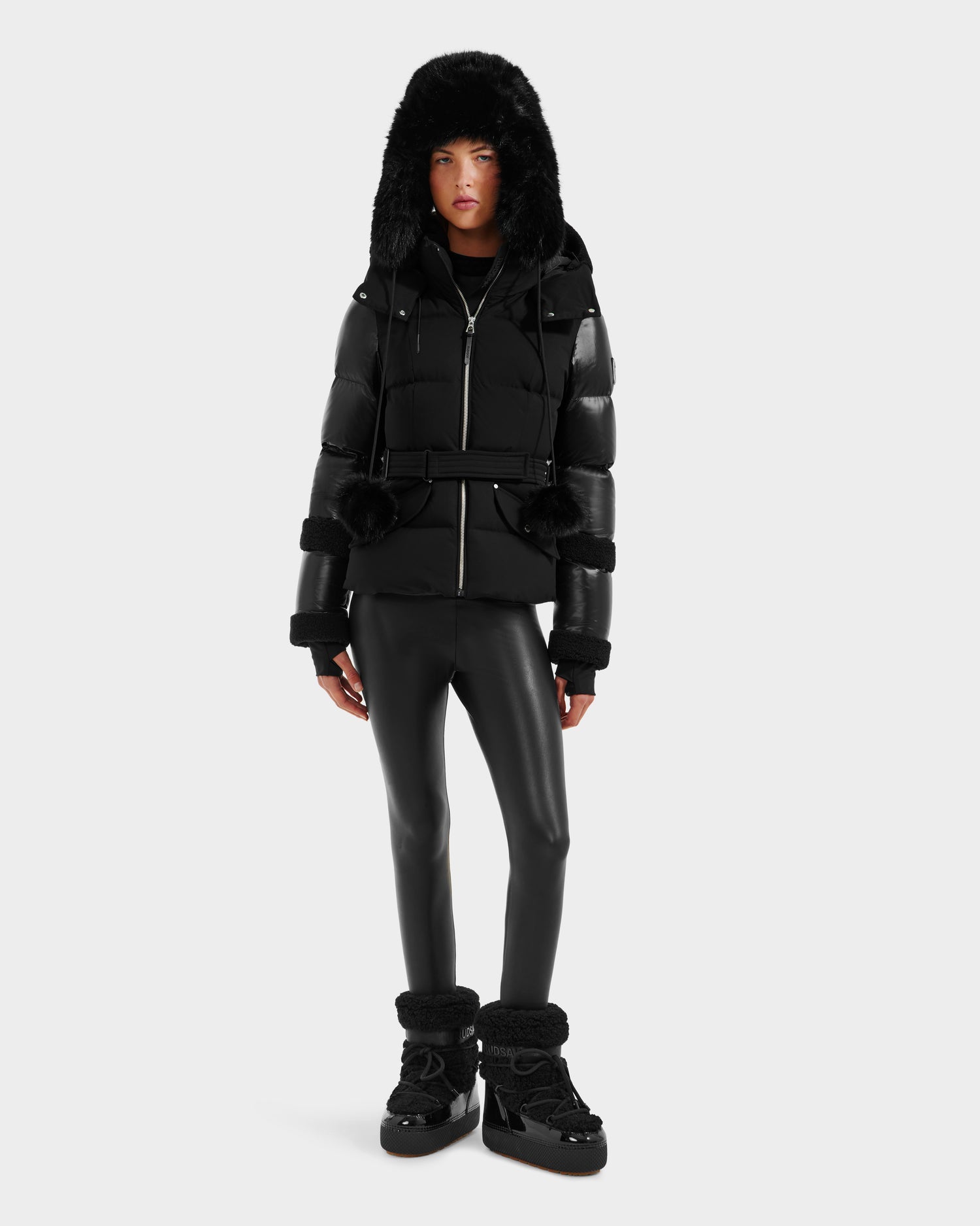 A person models the Rudsak AUDREY - 8124582 Black/Black jacket with RDS certified down, black leather-look pants, and black boots against a plain light gray background.
