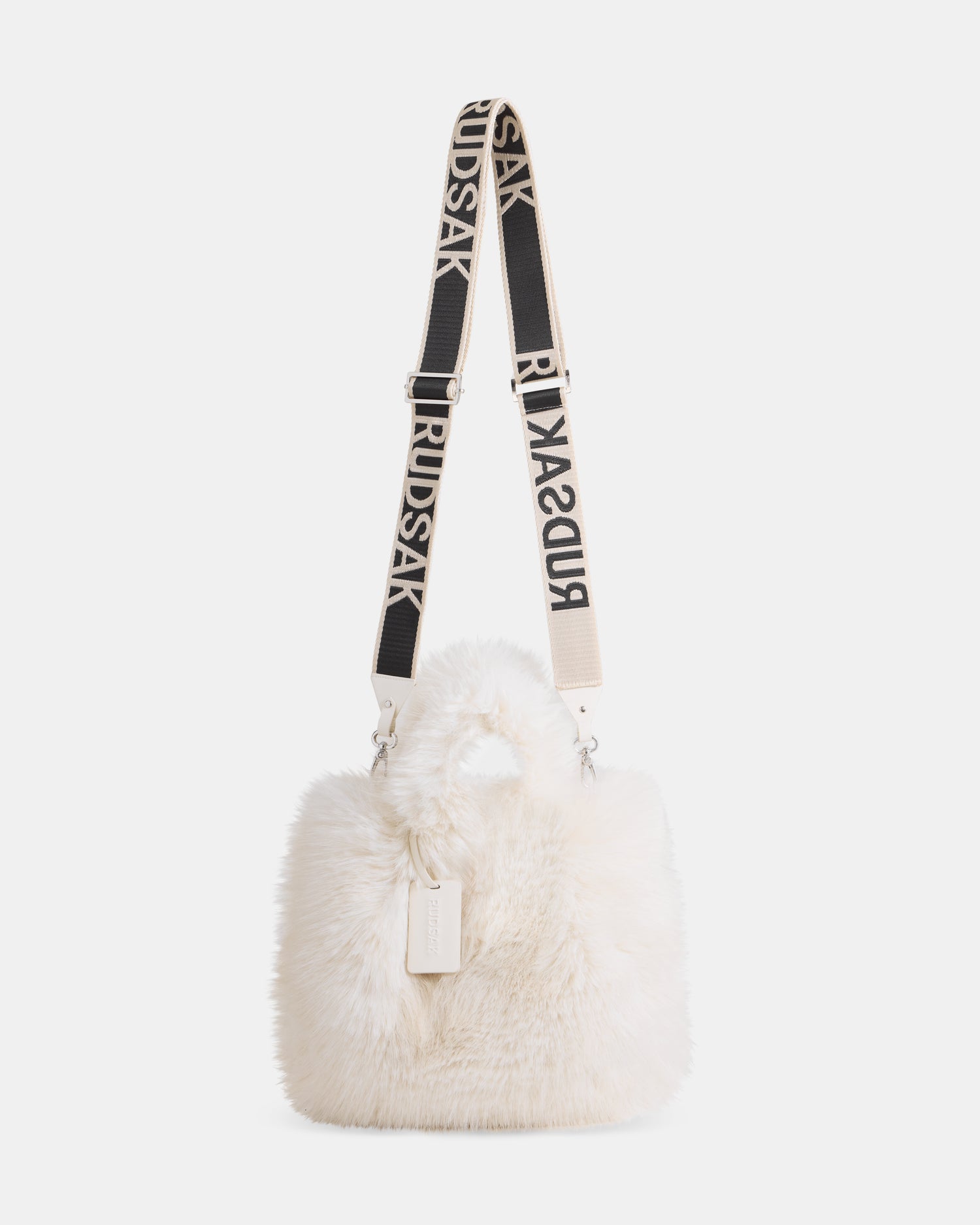 The CABAS - 8325545 Vanilla by Rudsak is a white faux fur mini tote with a bold-black-and-white adjustable “RUDSAK” strap and a rectangular tag—an eye-catching winter accessory for layering.