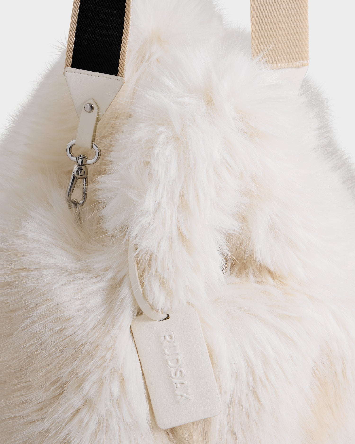 A close-up of the Rudsak CABAS - 8325545 Vanilla mini tote, featuring cream-colored faux fur, a beige strap, silver clasp, and an embossed leather tag—an ideal statement accessory for your winter look.