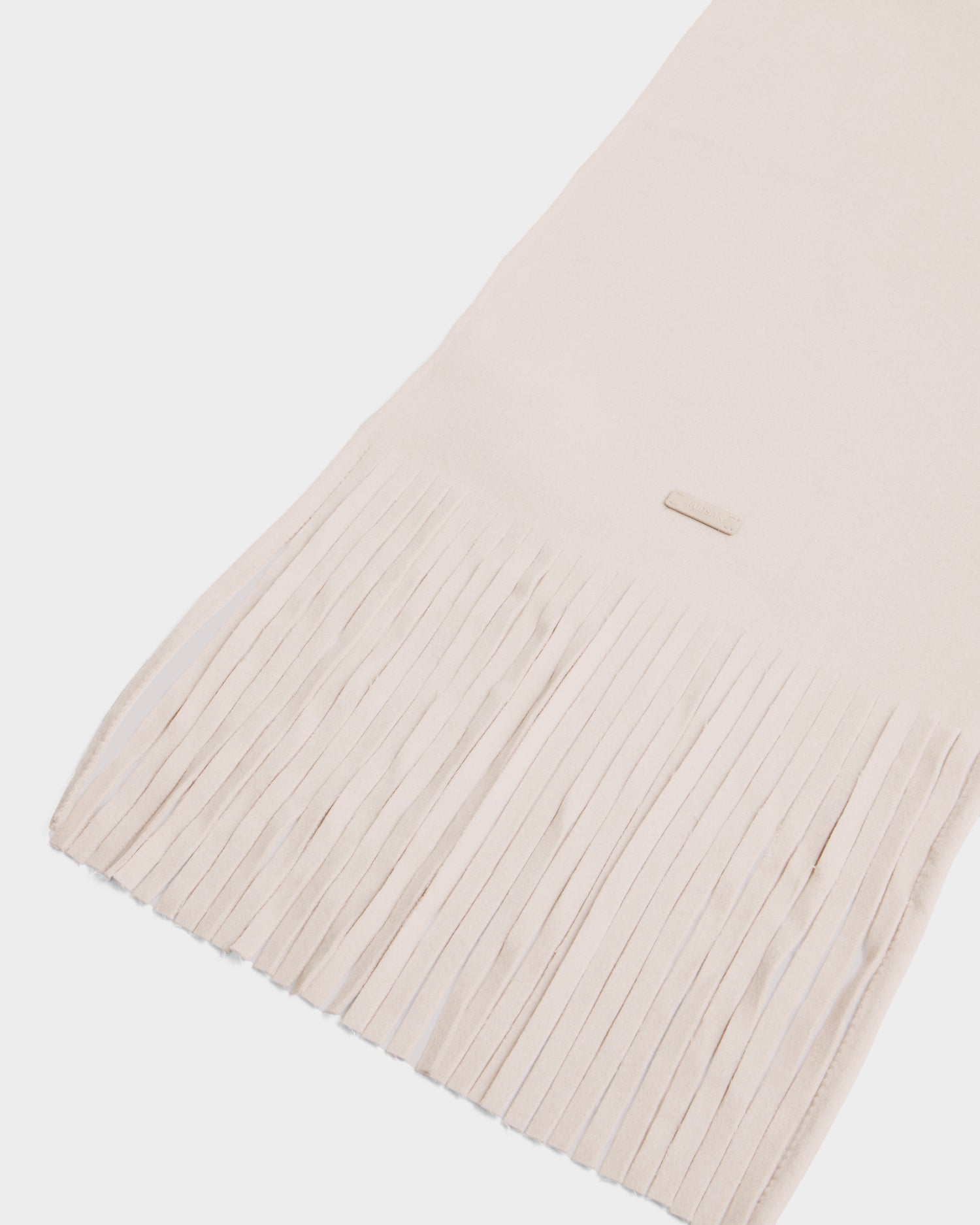 The Rudsak CALEN - 8425532 Vanilla is a light beige wool blend scarf with long, thin fringe ends—an ideal unisex accessory for cold weather, shown on a white background.
