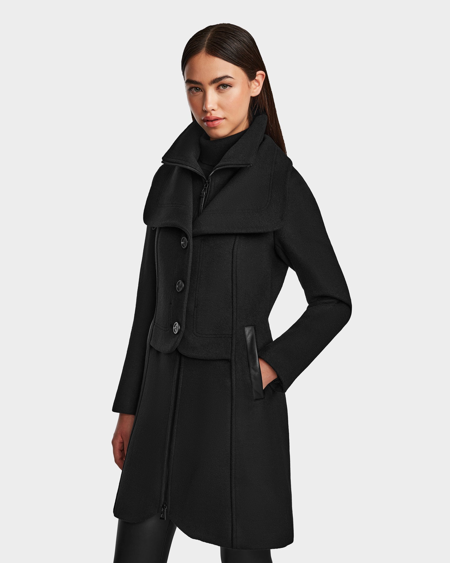 A woman in Rudsaks CAROLINE - L124543 Black, a knee-length vegan leather coat.